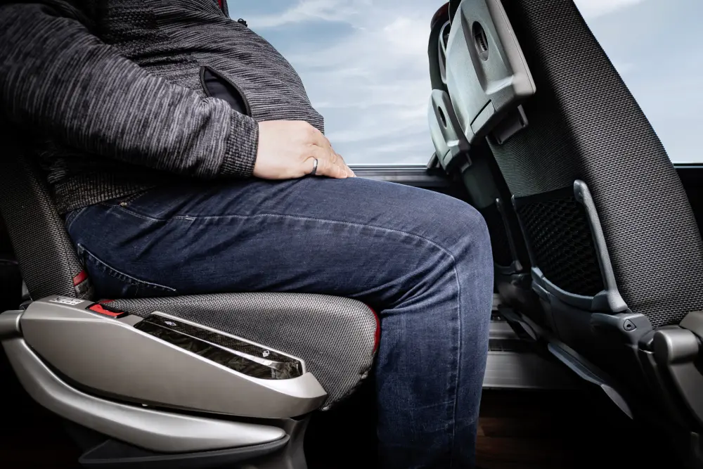 Eine Dame in einem Reisebus von Cepera demonstriert die Beinfreiheit.