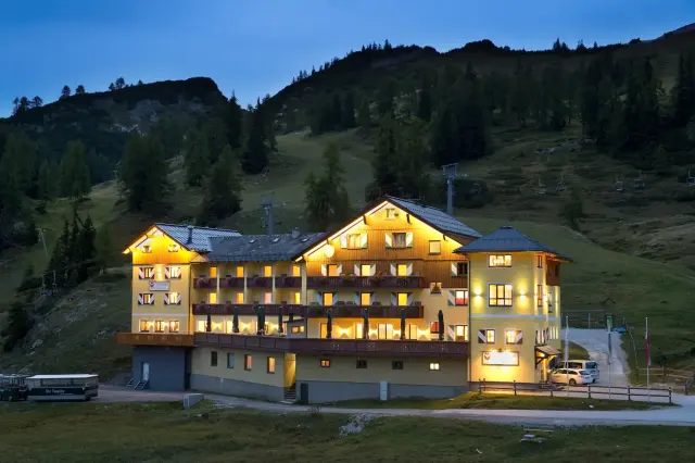 Beleuchtetes Hotel Hierzegger bei Nacht mit bewaldeter Hügellandschaft im Hintergrund